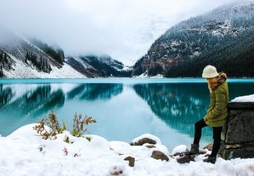 a woman standing in front of a lake in the winter