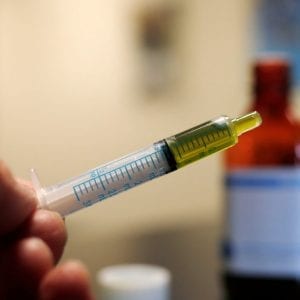 person dispensing cbd oil from a bottle