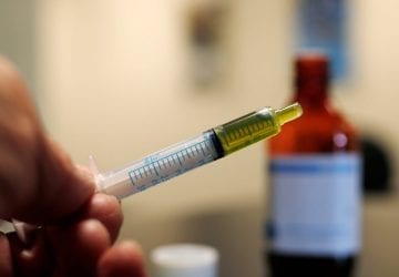 person dispensing cbd oil from a bottle