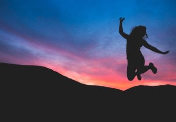 A woman jumping outdoors at sunrise