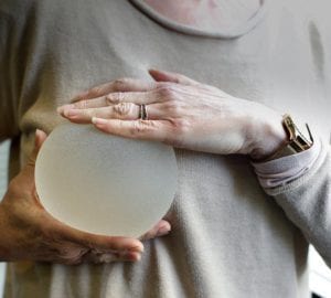 woman holding a breast implant