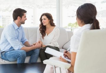 reconciled couple smiling at each other in the therapist office