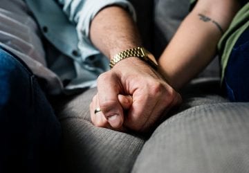 a couple holding hands on the couch