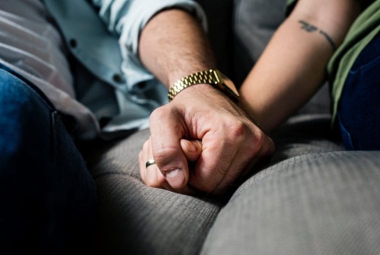 a couple holding hands on the couch