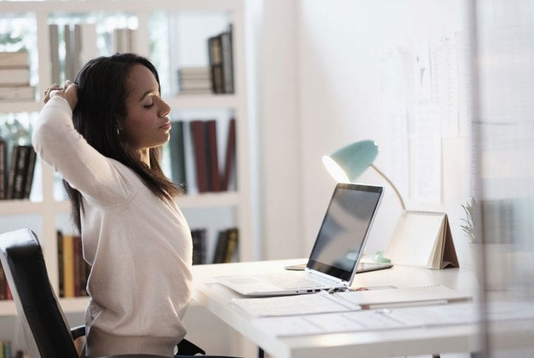 a woman stretching while working at her home computer