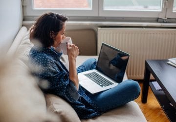 woman drinking coffee while on her computer