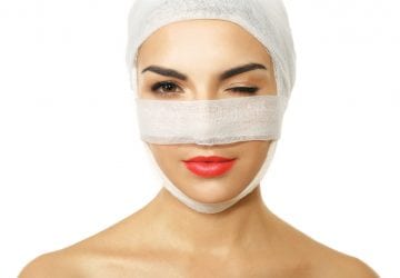 Young woman with a gauze bandage on her head and nose, isolated on white