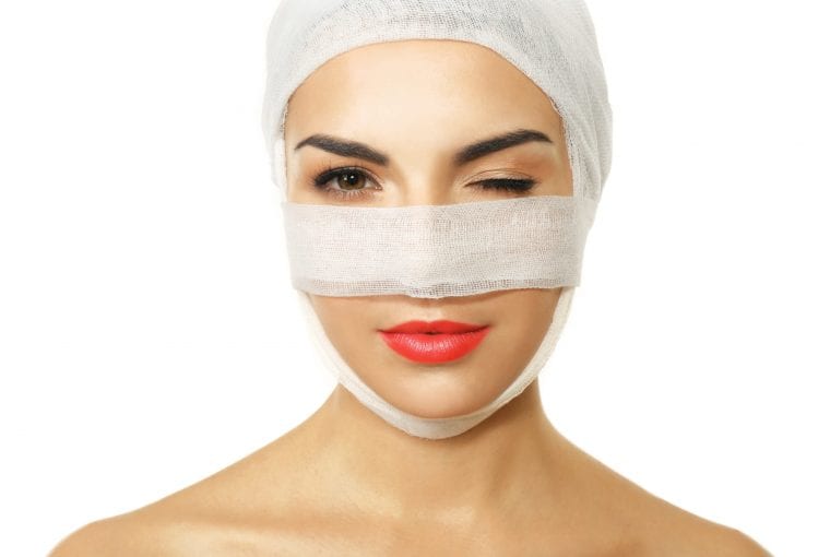 Young woman with a gauze bandage on her head and nose, isolated on white