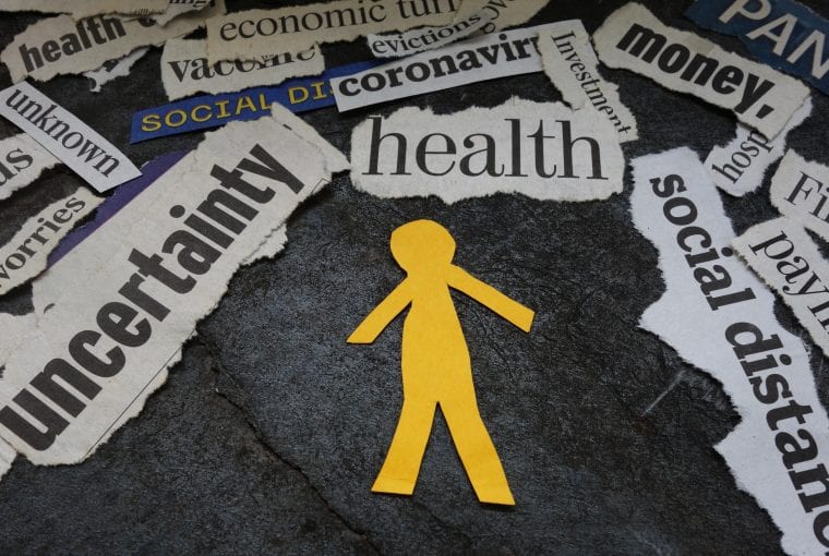 Paper man cutout surrounded by Corona Virus and economic news headlines