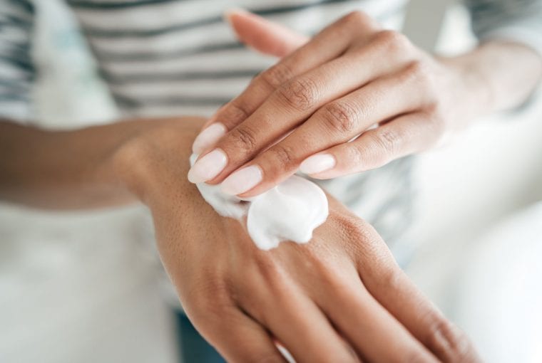 a woman applying cream to her hands