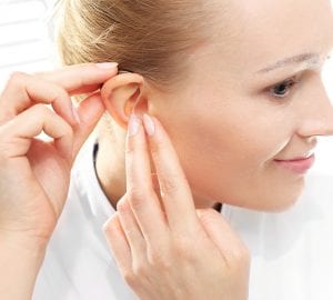 Young woman assumes a hearing aid