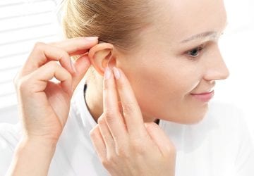 Young woman assumes a hearing aid