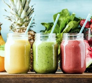 Freshly blended fruit smoothies of various colors and tastes in glass jars. Yellow, red, green. Turquoise blue background
