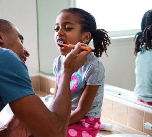 oral a dad helping brush his daughter's teeth