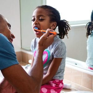 oral a dad helping brush his daughter's teeth
