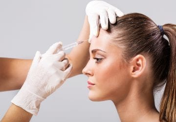Side view of a young woman receiving botulinum toxin injection.