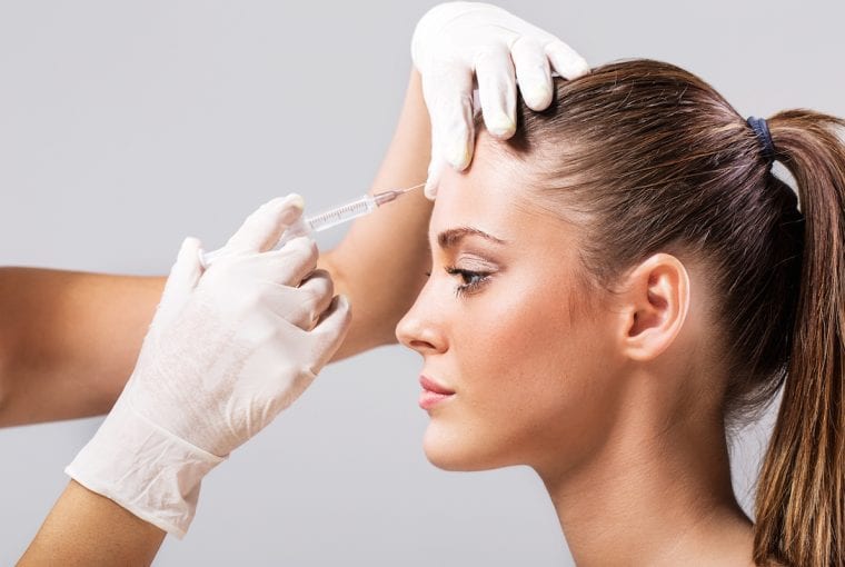 Side view of a young woman receiving botulinum toxin injection.
