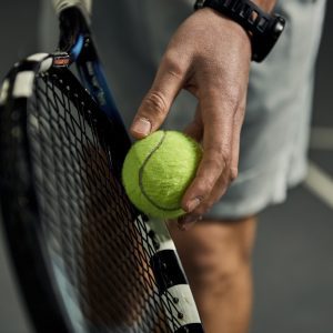 a person holding a tennis ball and racquet