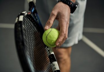 a person holding a tennis ball and racquet
