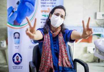 a woman wearing a mask and showing the peace sign with her fingers
