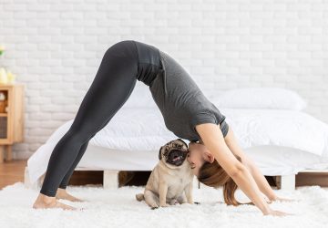 a woman kissing her dog and doing yoga