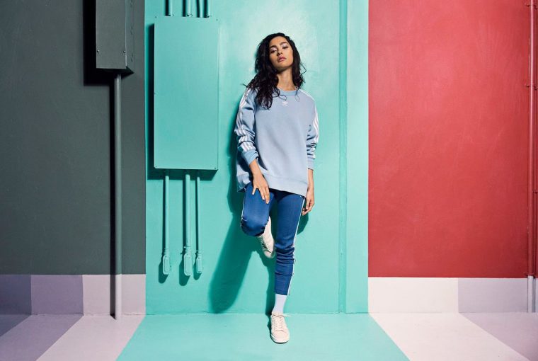 a woman standing against a wall in athletic apparel