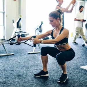 a woman doing bodyweight squats in the gym