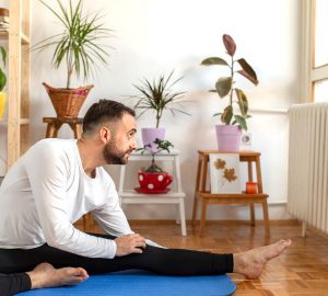 a man doing yoga and looking at his cat