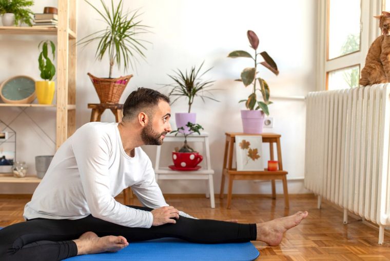 a man doing yoga and looking at his cat