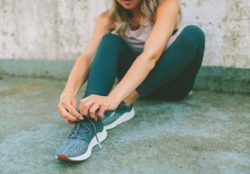 a woman lacing up her shoes before a workout.