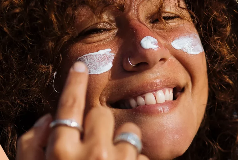 a woman putting sunscreen on her face