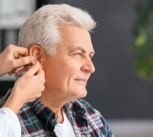 a man having a hearing aid inserted