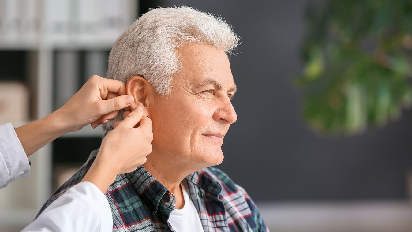 a man having a hearing aid inserted