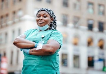 a female nurse in her uniform standing in front of a building