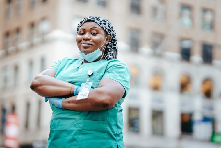 a female nurse in her uniform standing in front of a building