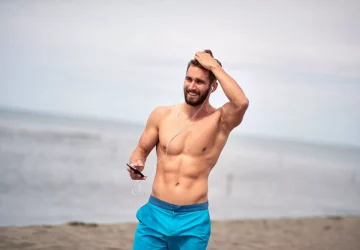 a man with no shirt at the beach