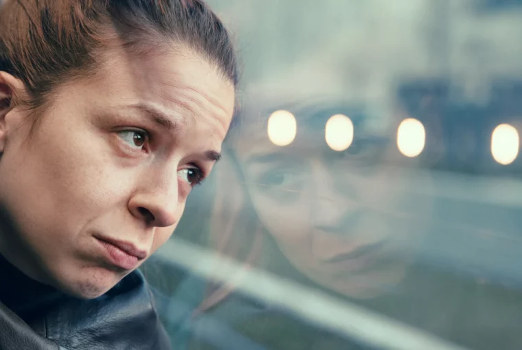 a sad woman looking out the window of the bus on a gloomy day