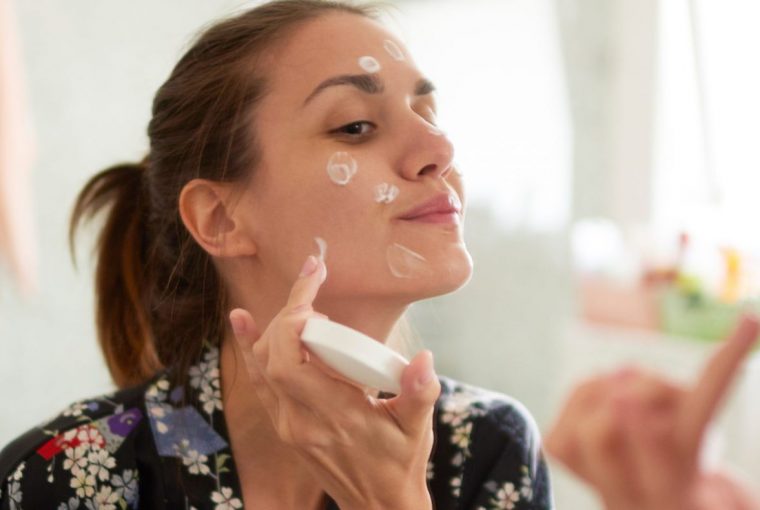 a woman applying skincare products to her face