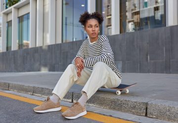 a woman sitting on a curb with great street style