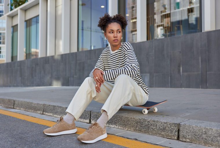 a woman sitting on a curb with great street style