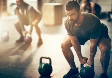 a strong man with a beard doing a workout with a kettlebell