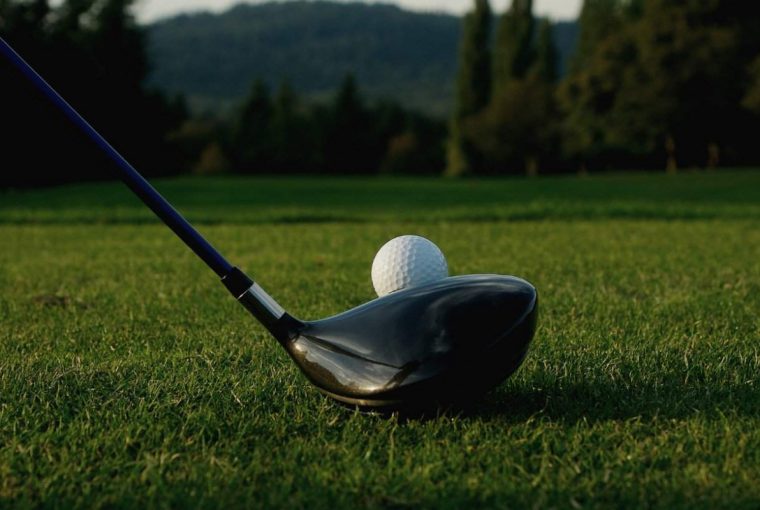 a golf ball lined up with a driver