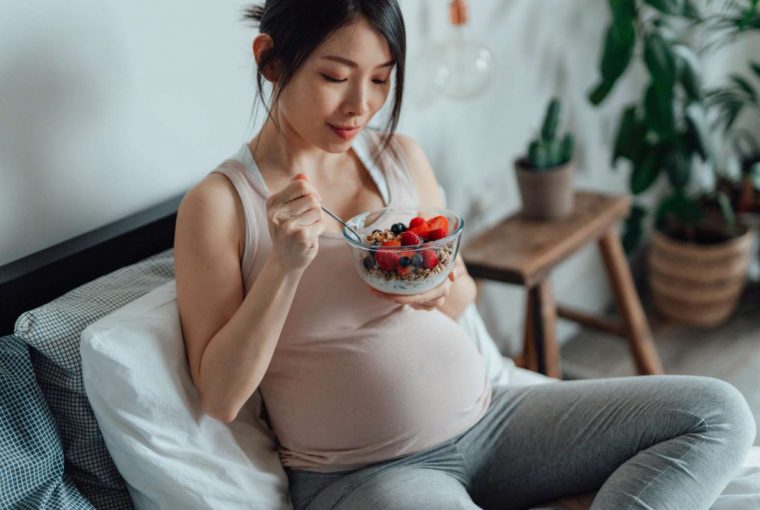 a pregnant woman eating a healthy breakfast