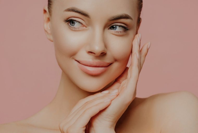 a youthful looking woman staring off camera with her hands on her face