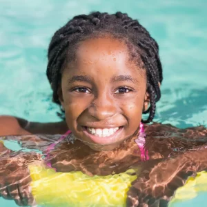 a young smiling girl swimming in a pool