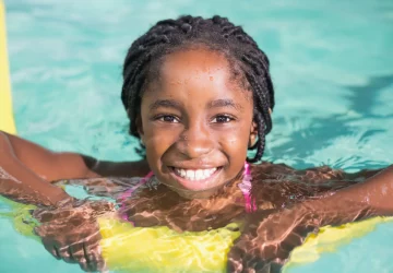 a young smiling girl swimming in a pool