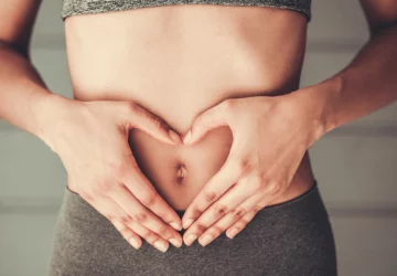 a woman forming her hands into the shape of a heart over her stomach