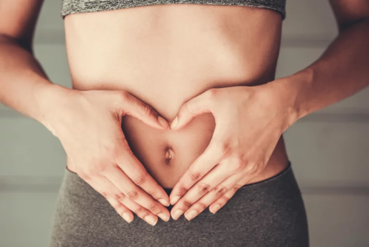 a woman forming her hands into the shape of a heart over her stomach