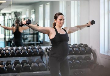 a pregnant mom lifting weights in the gym