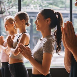 Group of young people practicing yoga In the prayer position at gym, Concept of relaxation and meditation